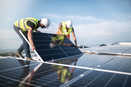 Team von zwei Ingenieuren, die Sonnenkollektoren auf dem Dach installieren