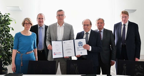 Gruppen von Menschen, welche einen unterzeichneten Vertrag in die Kamera halten